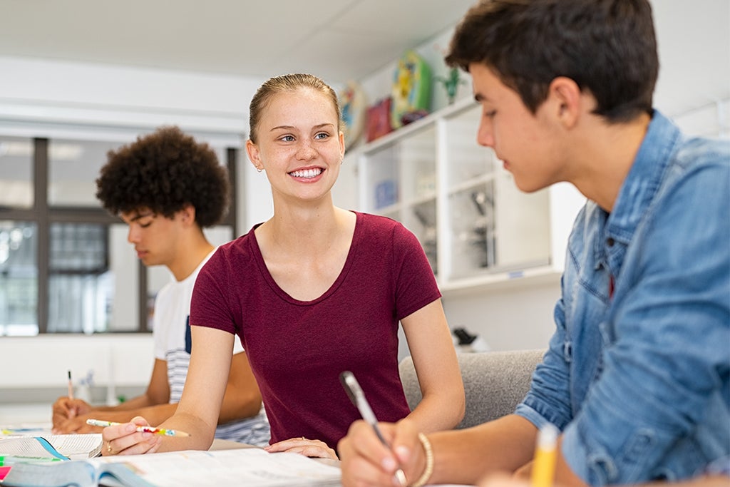 Two high school students work on an assignment together in the classroom.